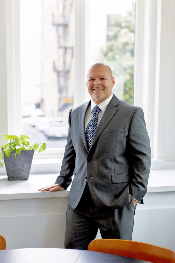 Brandon Adams wearing suit in office meeting room